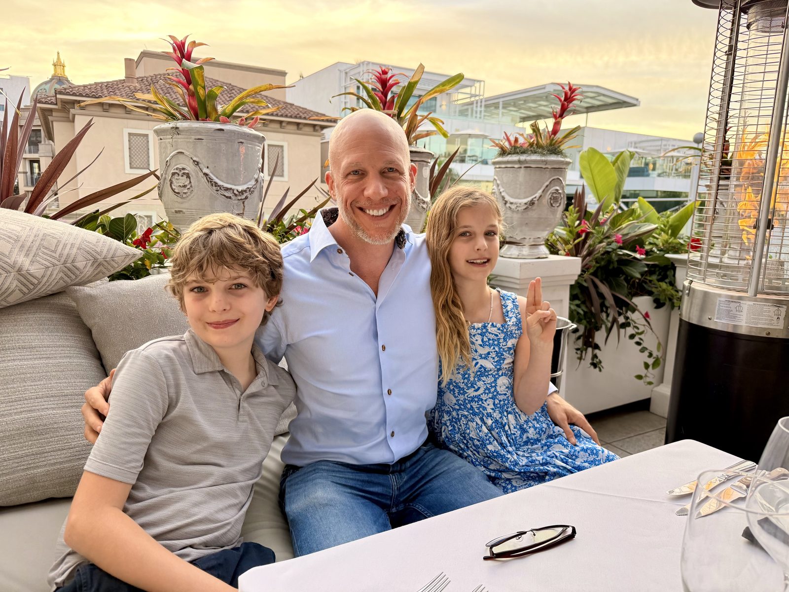 David and his two kids at a table outdoors, smiling