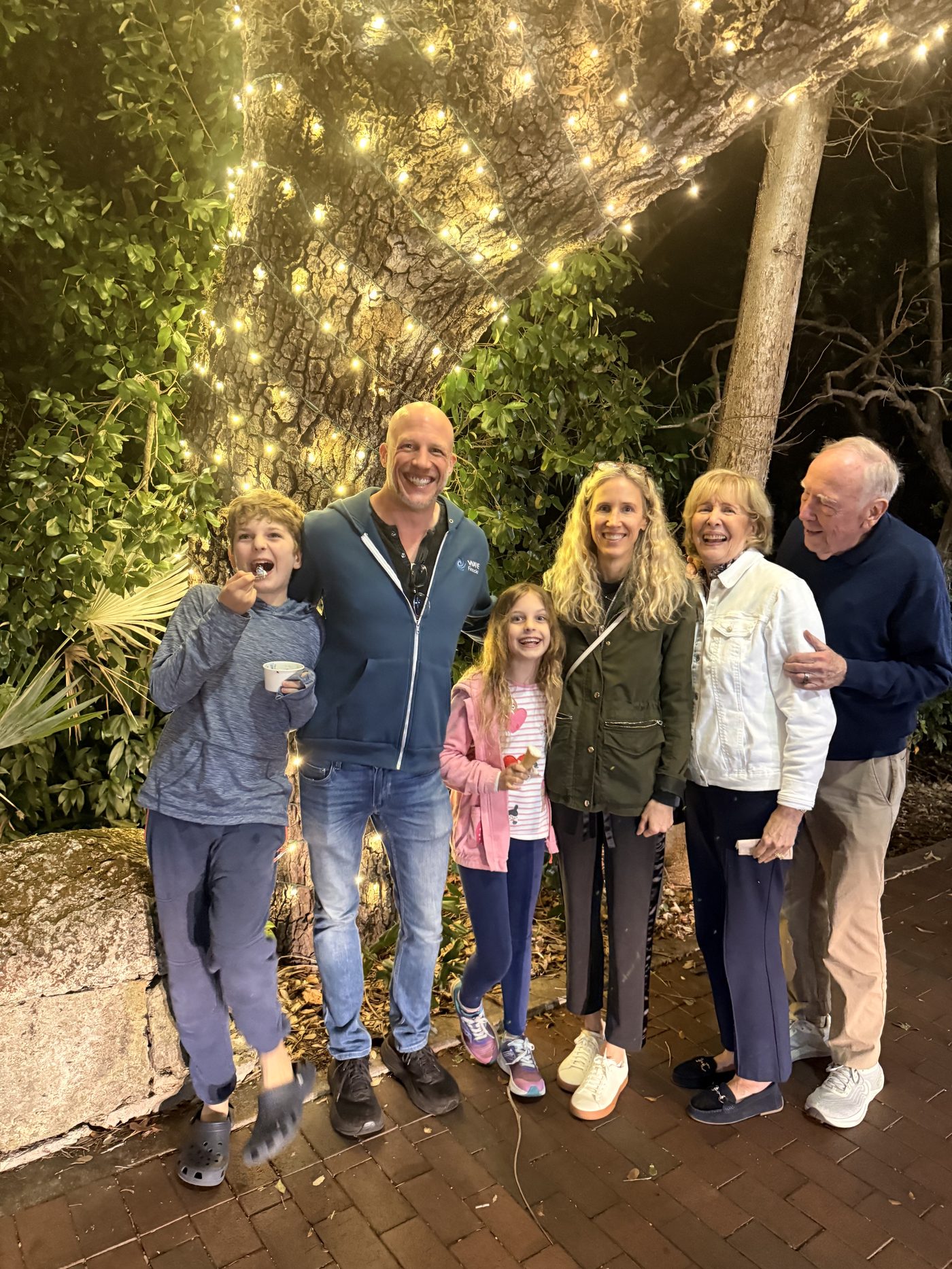 Three generations of the family together under a tree strung with lights